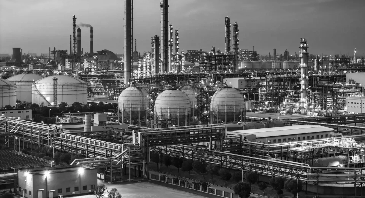 Refinery processing towers and pipework, shown in monochrome